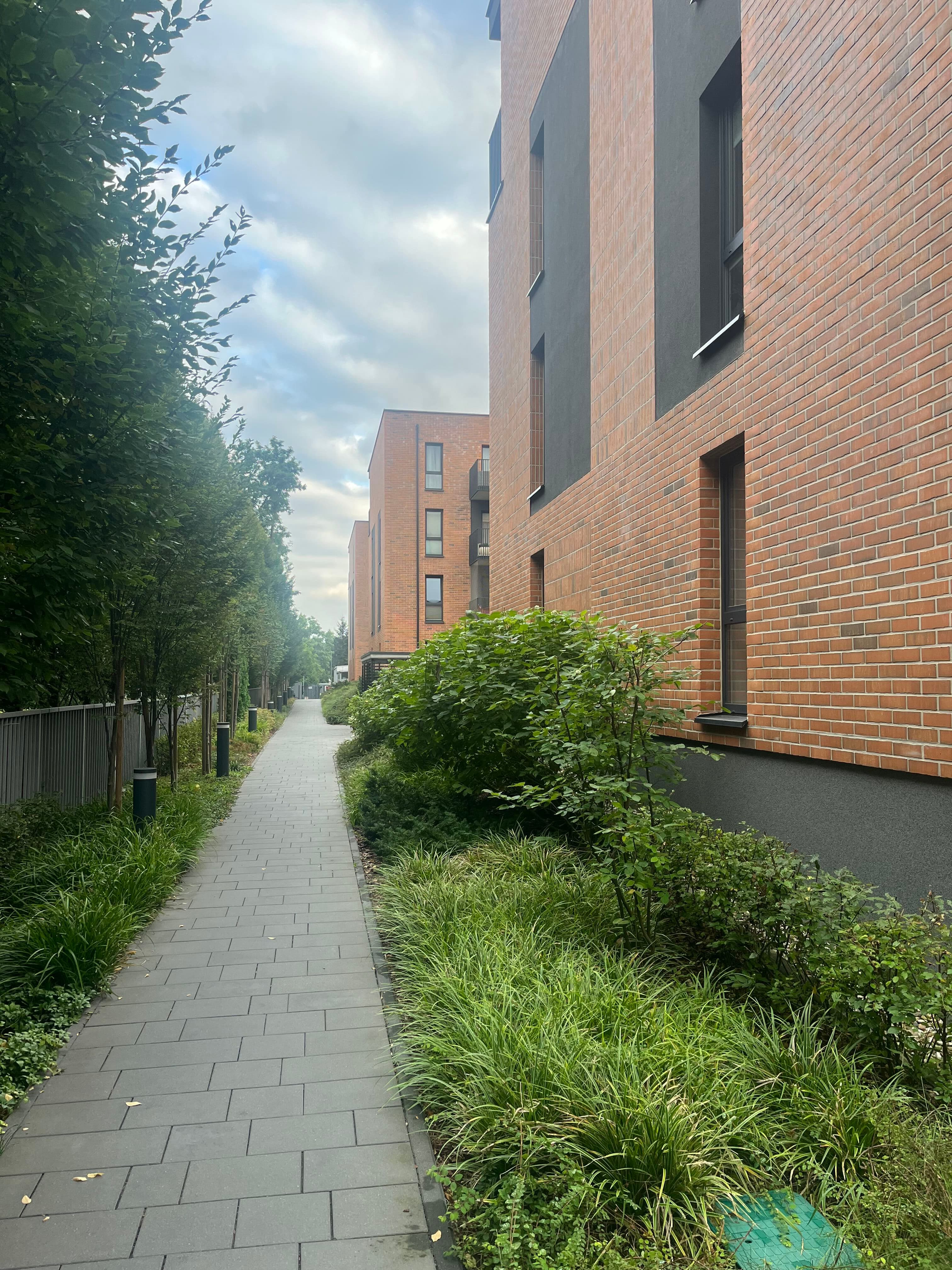 Path along a brick apartment façade.