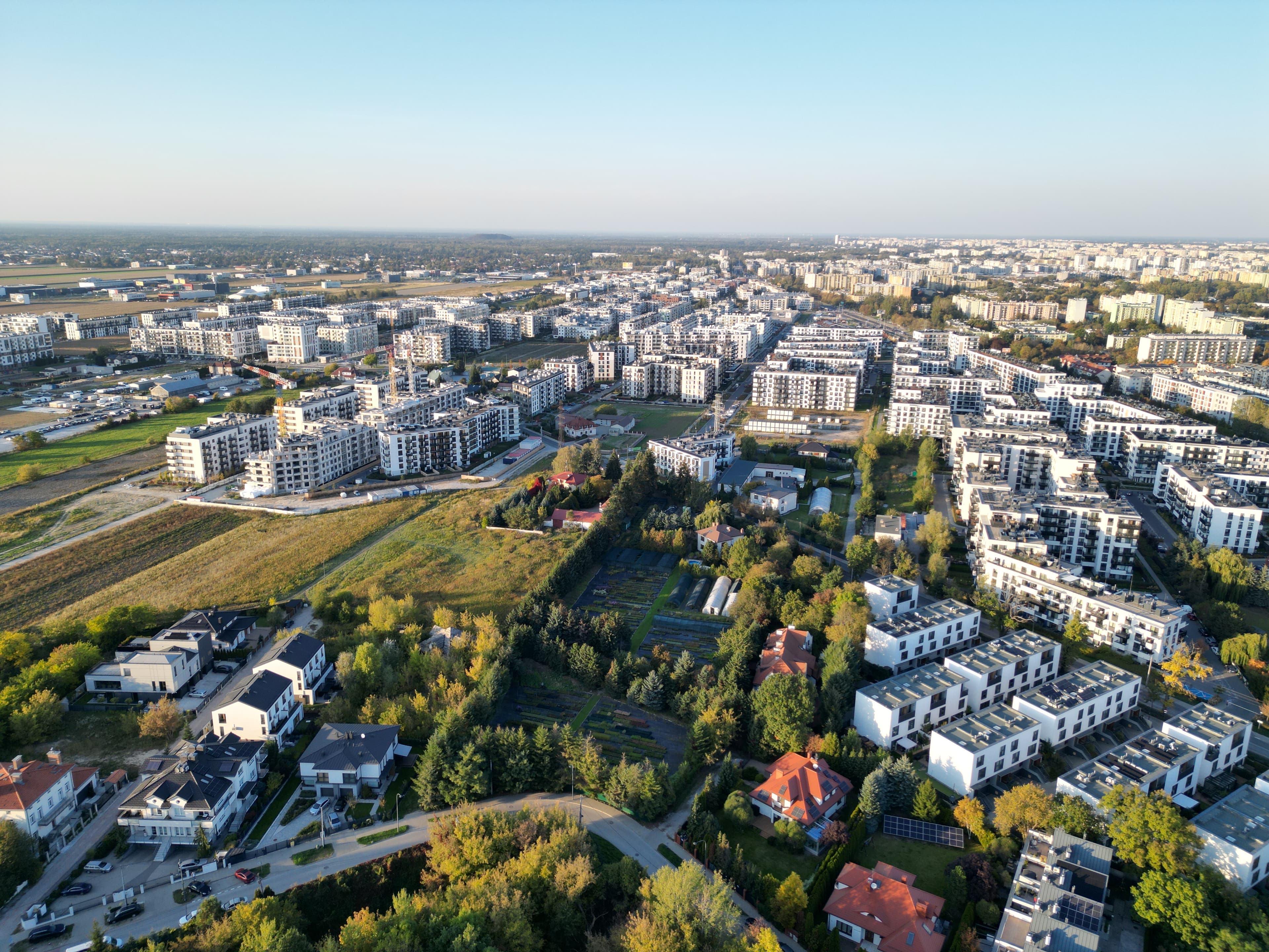 Wide aerial of Chrzanów — new mid-rise estates, private houses and remaining open fields.