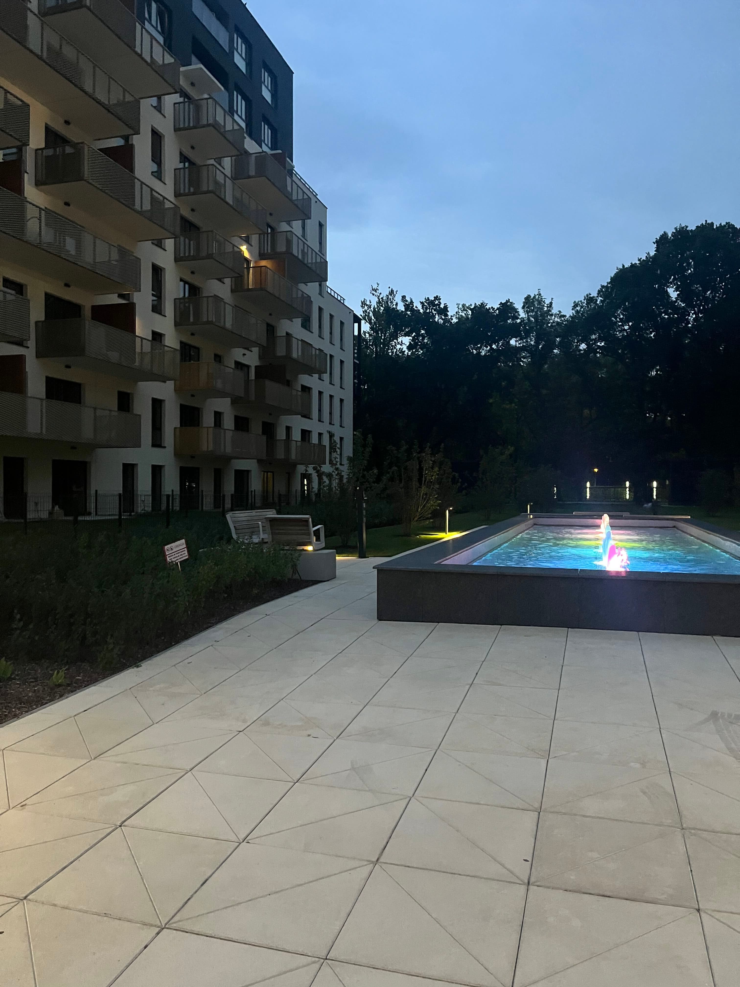 Colour-lit fountain on the Stage II plaza at dusk.