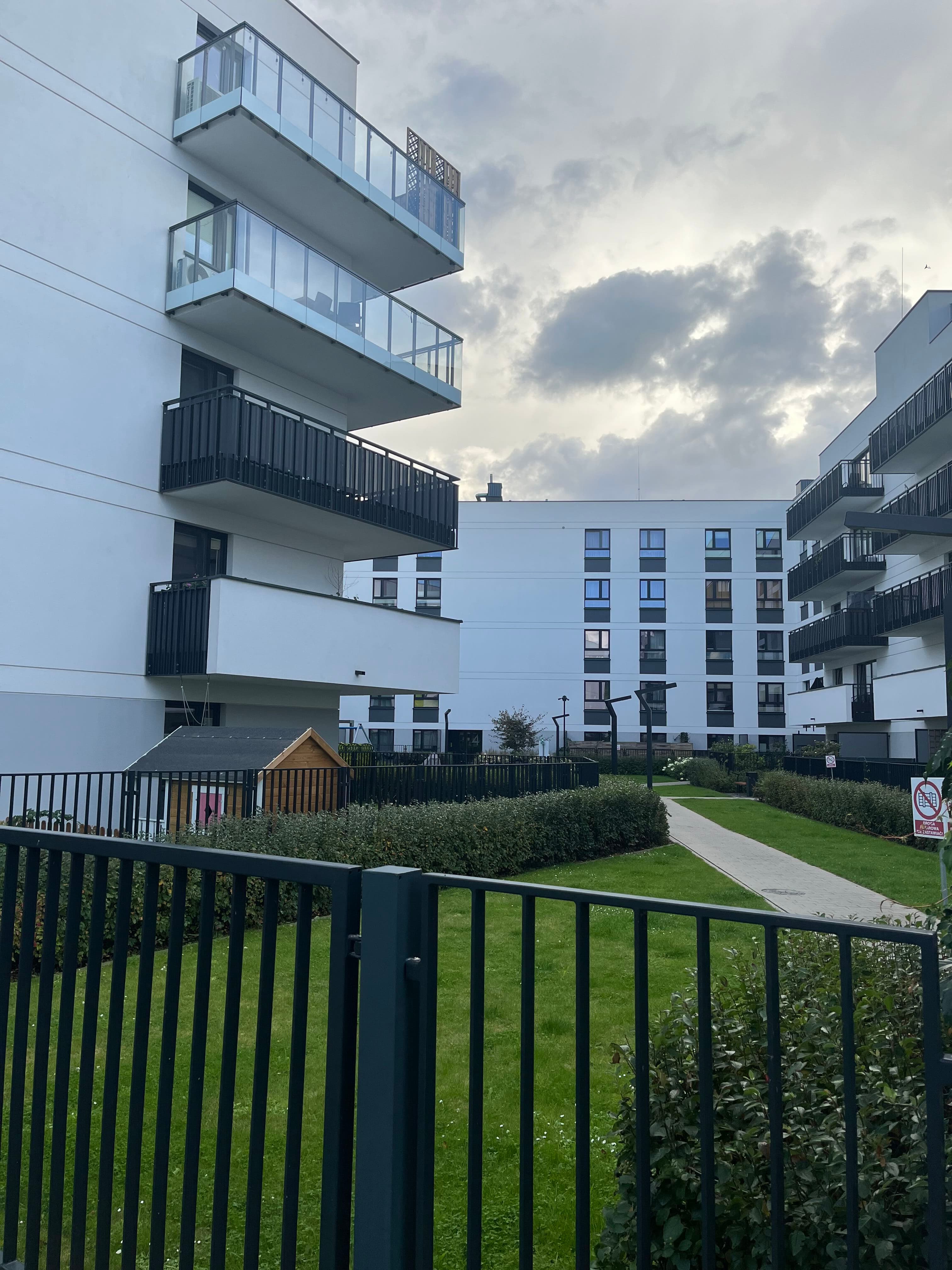 Courtyard lawn and wooden playhouse between Metro Zachód buildings.