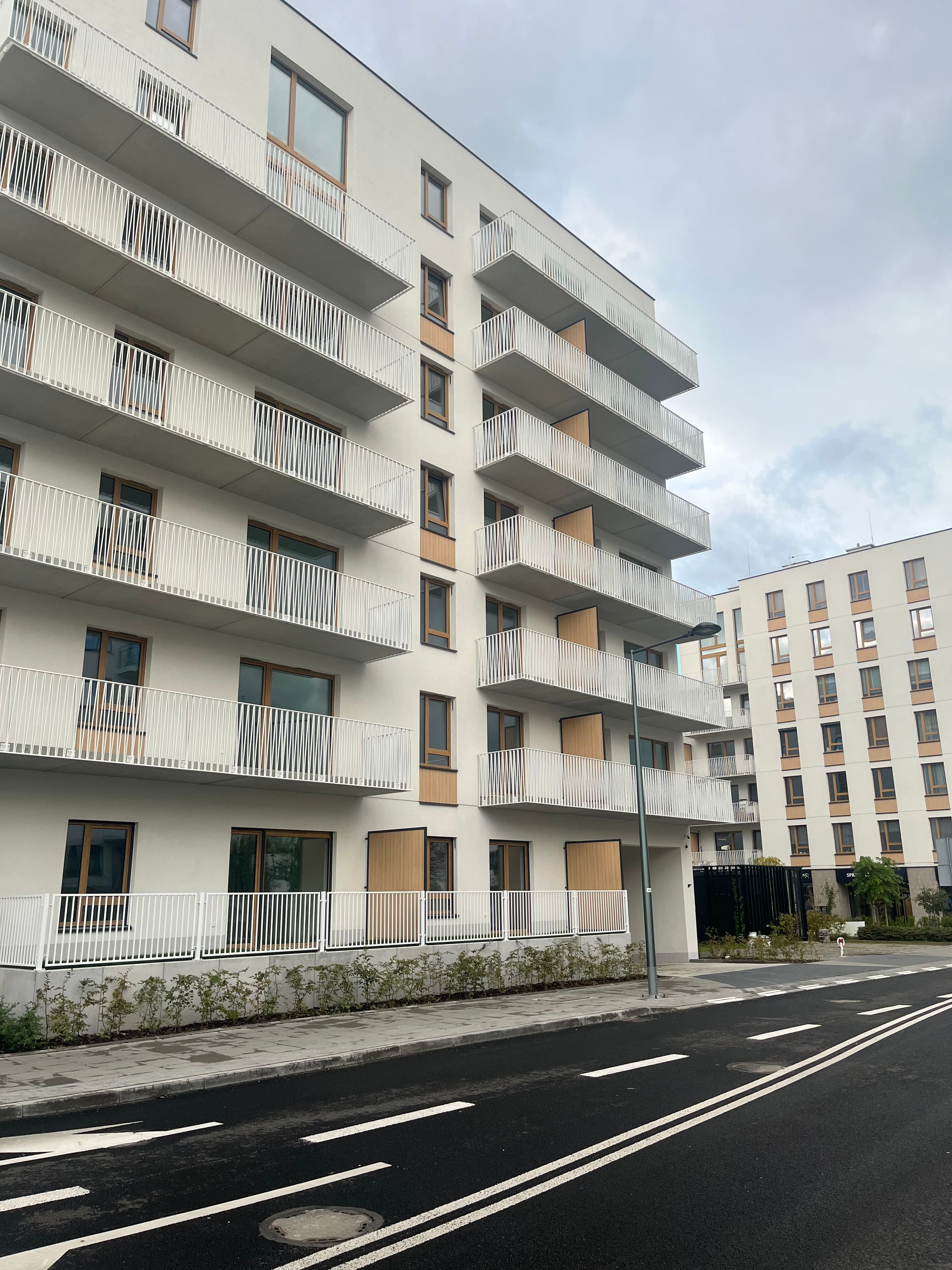 Neowo street façade — white plaster with wood accents and balcony screens.