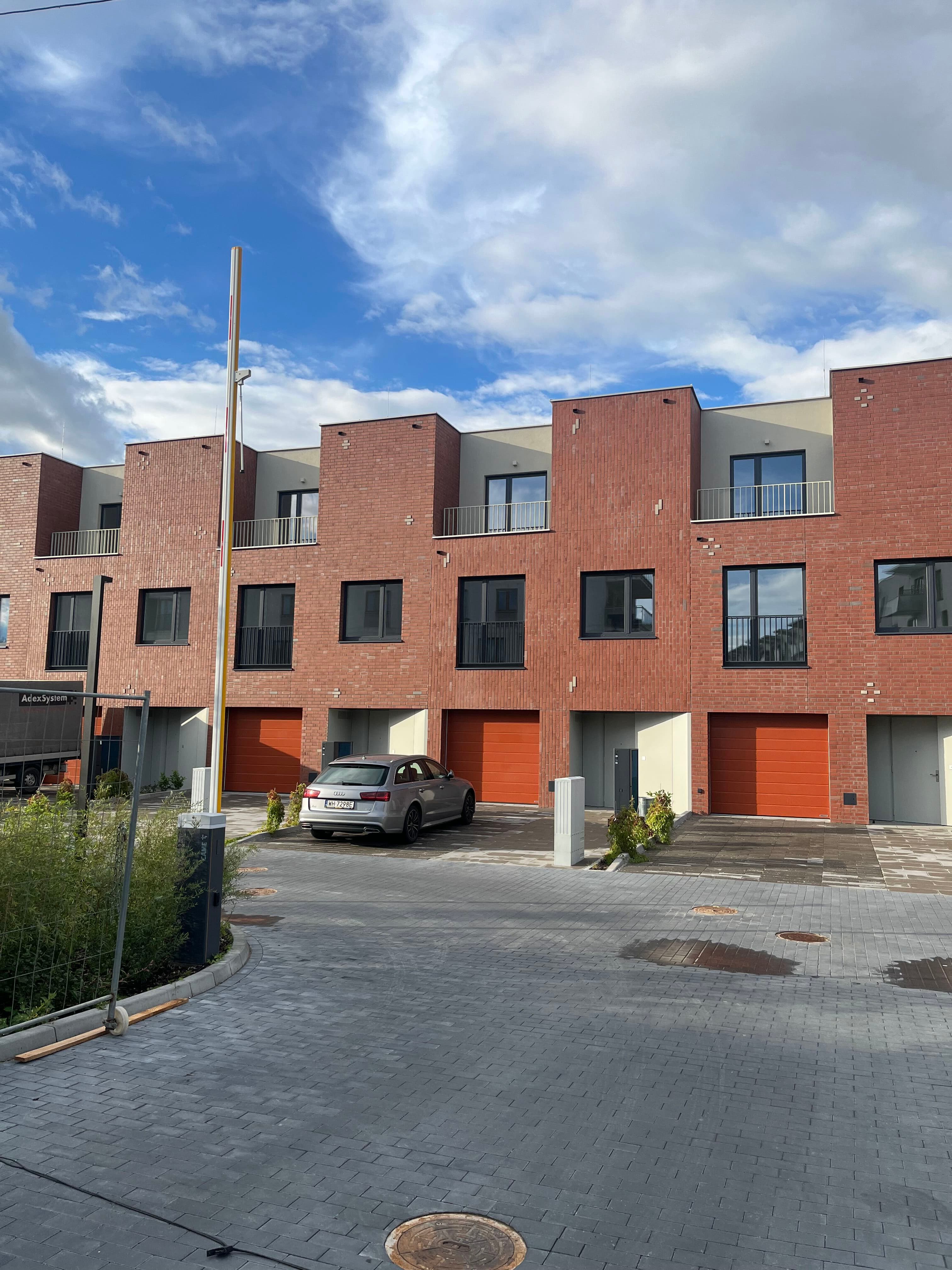 Domy façades up close — brick upper floors, orange garage doors, and gated driveway.