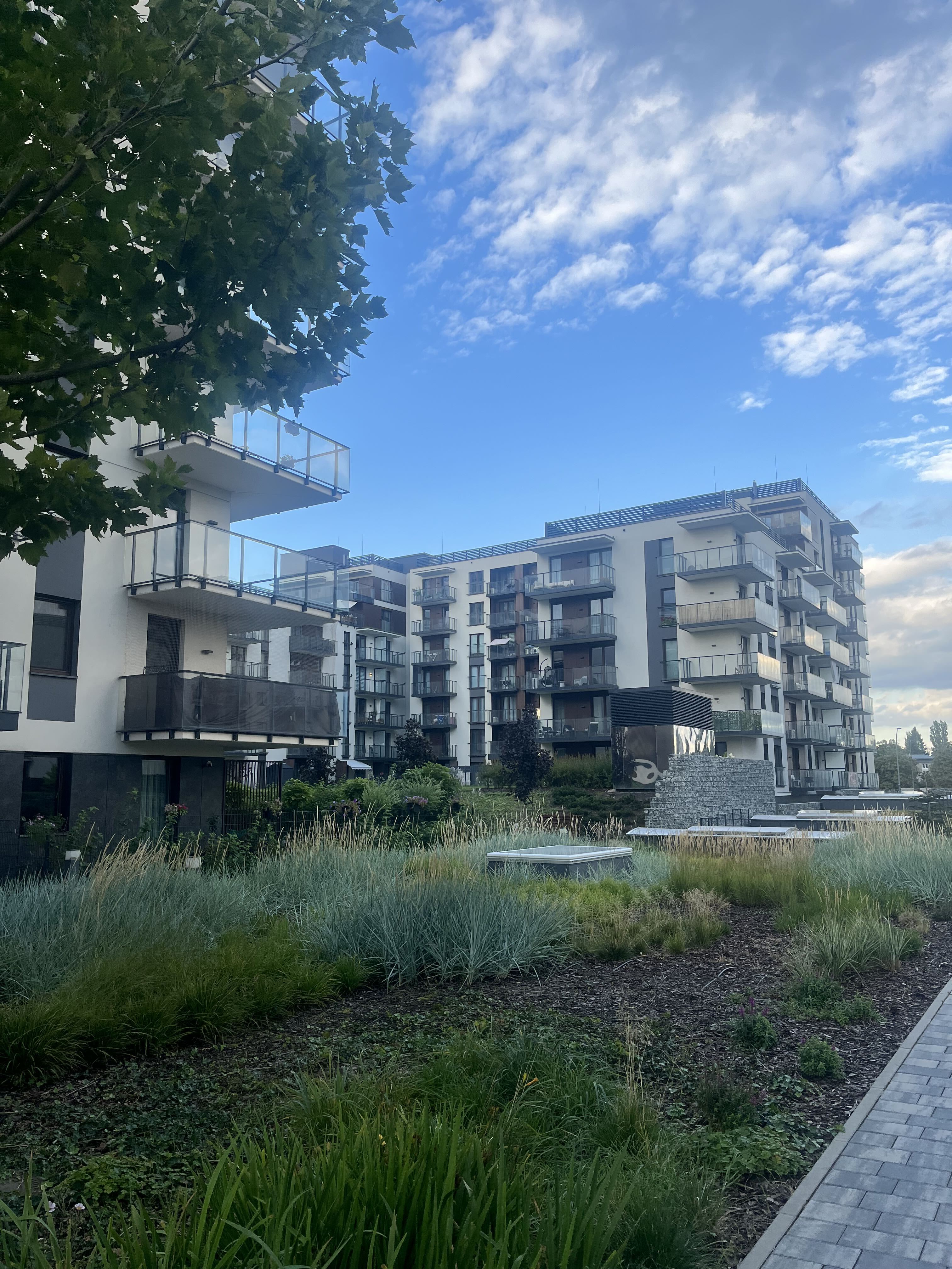 Courtyard at Bulwary Praskie with a shallow water feature, planted beds and balconies on the white blocks