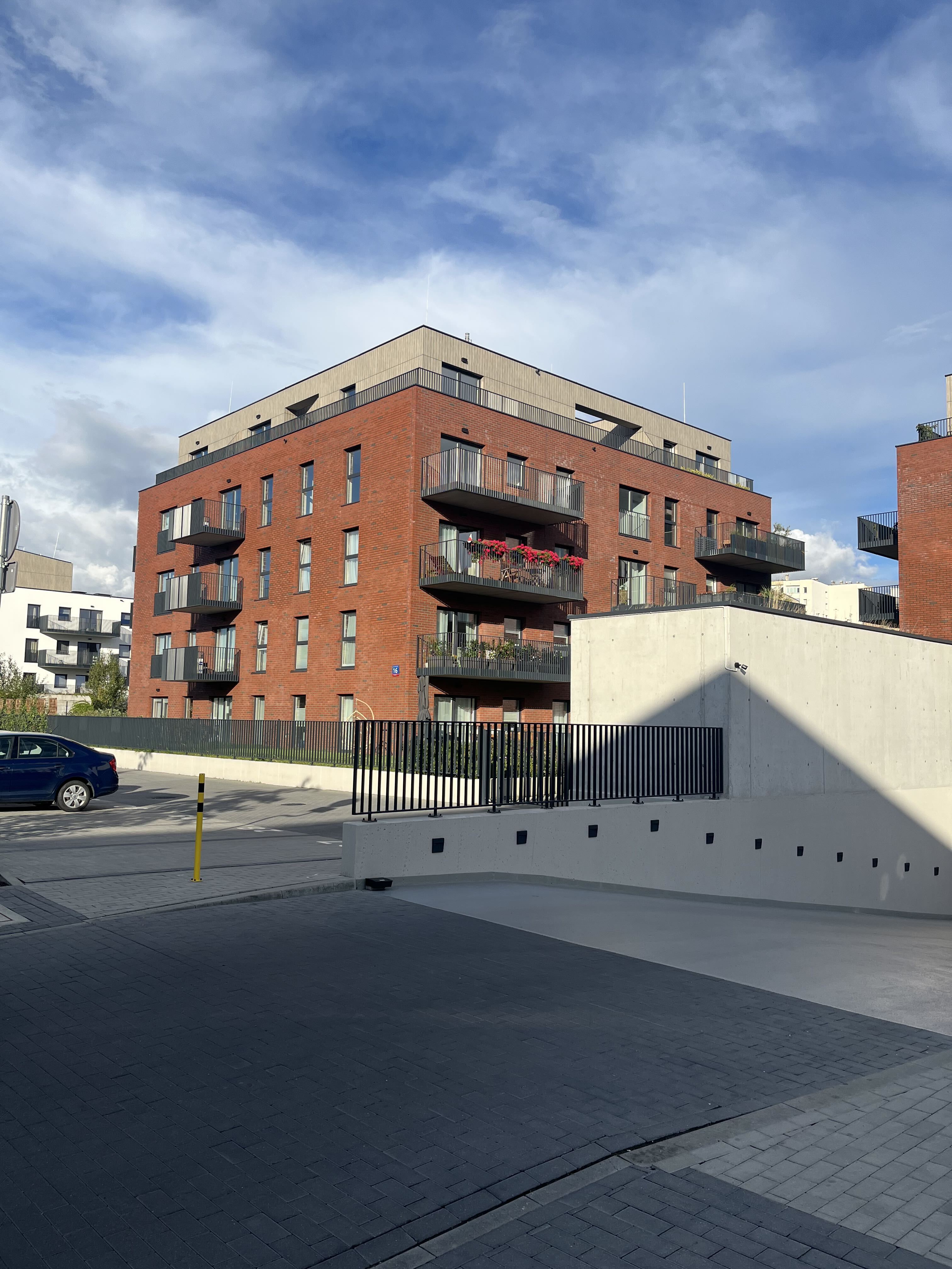 Stage I brick façade with wood-clad top floor and underground parking ramp