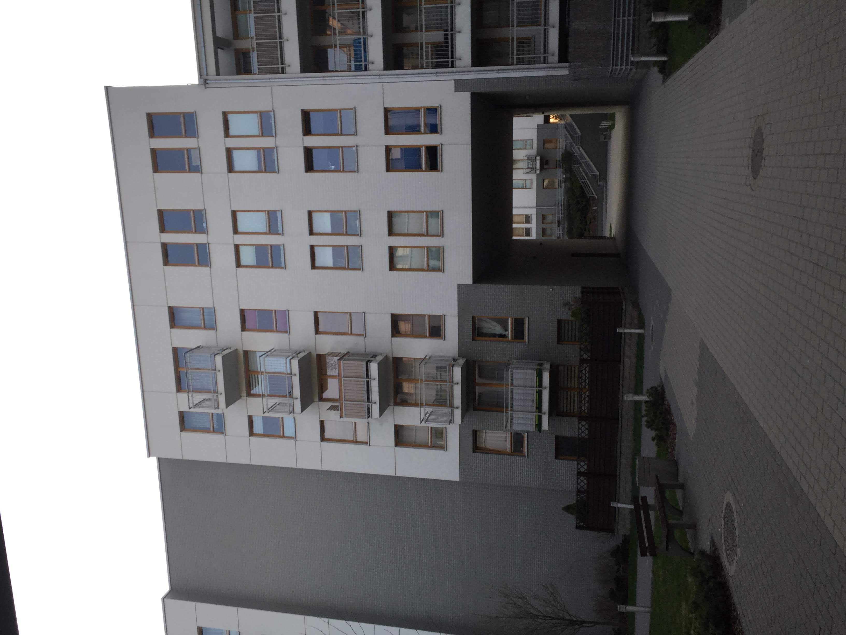 White Zielona Italia block with wood-framed windows, balconies and a passage through the building